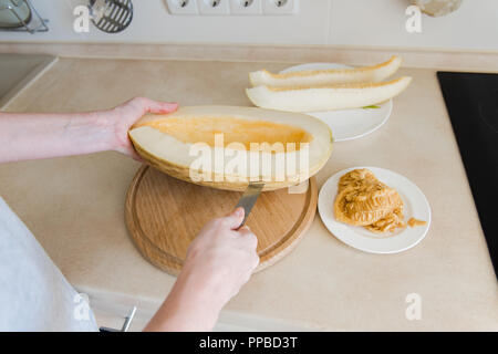 Frau cut Melone und sauber aus Samen Stockfoto