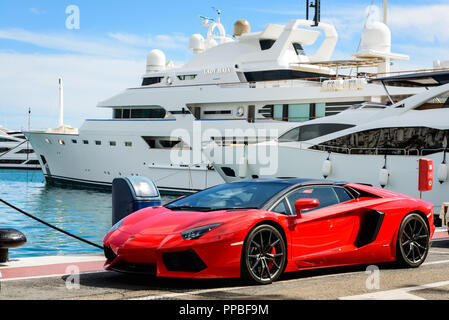 Vorderansicht eines roten Super Sport Auto (Lamborghini) neben luxuriösen Yachten in der Marina von Puerto Banús günstig geparkt. Stockfoto