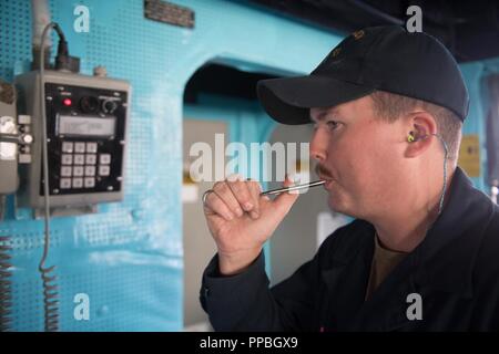 Pazifik (Aug. 23, 2018) der Bootsmann Mate Seemann Conor Diebel, aus Winter Park, Florida an der Arleigh-Burke-Klasse geführte Anti-raketen-Zerstörer USS Chung-Hoon (DDG93), verwendet der Bootsmann pfeife Abendessen Zeit zu signalisieren. Chung-Hoon unterwegs ist die Durchführung von Routineaufgaben als Teil der Carrier Strike Group (CSG) 3 in den USA 3 Flotte Bereich der Operationen. Stockfoto