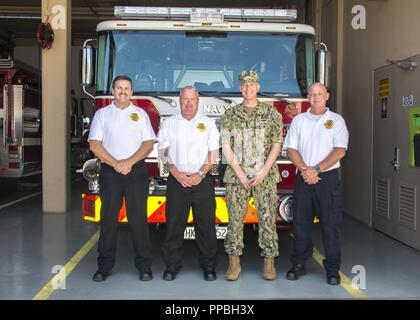 NAVAL SUPPORT ACTIVITY Souda Bay, Griechenland (28. August 2018) Von links, Steven Grau, stellvertretender Leiter der Feuerwehr für die Ausbildung, Patrick Murphy, stellvertretender Leiter der Feuerwehr, Kapitän Ryan T. Tewell, kommandierender Offizier Naval Support Activity Souda Bay, Griechenland, und Christopher Lindsay, stellvertretender Leiter der Feuerwehr, sammeln für ein Gruppenfoto vor dem neuen Feuerwehrauto an Bord der Installation, 27. August 2018. Eine langjährige Tradition auf dem Gebiet der Feuerwehr, der "nassen", handelt es sich um einen zeremoniellen Prozess, bei dem die Feuerwehrmänner, die offiziell in Dienst ein neues Feuer Apparate durch Salbung es mit Wasser aus dem scheidenden Uni gesprüht Stockfoto