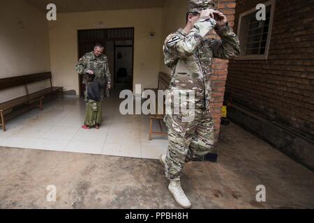 Us-Armee Maj. Foster Knowles, Mitte, Civil Affairs Officer, erhält eine Umarmung von einem Kind während einer Tour der Masaka Health Center Services während der MEDRETE 18-5 bei Kigali, Ruanda, 23.08.2018. MEDRETE 18-5 ist die erste gemeinsame Anstrengungen für eine medizinische Bereitschaft Übung zwischen der Ruandischen Regierung und der US-Armee Afrika. Die Übung ist Teil einer Reihe von medizinischen Readiness Training, dass die US-Armee Afrika geplant ist innerhalb der verschiedenen Länder in Afrika zu erleichtern, und dient als eine Chance für die Partnerschaft der Streitkräfte auf ihre allgemeine Chirurgie und Unfallchirurgie Fähigkeiten stärken schärfen und Stockfoto