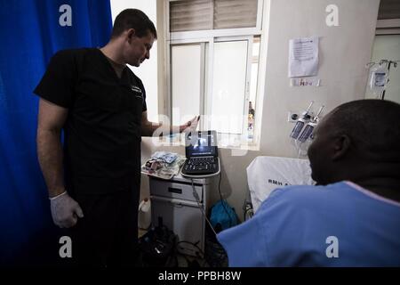 Us-Armee MAJ Thomas Nessler, Notarzt und Ultraschall und Kollegen in Fort Hood, Texas zugeordnet, illustrieren eine Diagnose eines Patienten von einem Ultraschall Bild bei MEDRETE 18-5 an der militärischen Krankenhaus Ruanda, Kigali, Ruanda, Aug 24., 2018. MEDRETE 18-5 ist die erste gemeinsame Anstrengungen für eine medizinische Bereitschaft Übung zwischen der Ruandischen Regierung und der US-Armee Afrika. Die Übung ist Teil einer Reihe von medizinischen Readiness Training, dass die US-Armee Afrika geplant ist innerhalb der verschiedenen Länder in Afrika zu erleichtern, und dient als eine Chance für die Partnerschaft Streitkräfte abzuziehen und Stockfoto