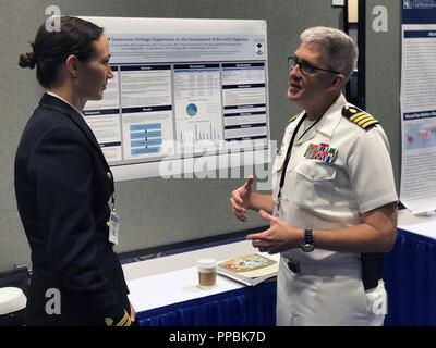 Kapitän Adam Armstrong, Commander, Naval Medical Research Center (NMRC), diskutiert mit Leutnant Christie Joya, Forscher zu sein, U.S. Naval Medical Research Center Nr. 6 in Lima, Peru, (NAMRU-6), wie die Marine Medizin R&D Enterprise anvertraut wird hoher Wert, high-impact Research Produkte zu unterstützen und Schützen der heutigen warfighters während der 2018 militärische Health System Research Symposium (MHSRS). Stockfoto