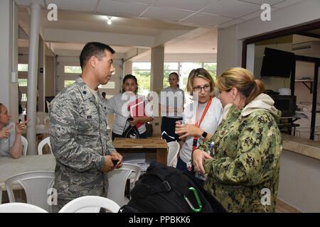 Air National Guard Oberstleutnant William Wong, 183 d-Flügel, Maj. Erin Aerahamsen, 143d Medical Group und die US-Navy Reserve Lt.Cmdr. Lynda Schubert, Expeditionary medizinischen Einrichtung, Camp Pendleton, gegenseitig aktualisieren, bevor Sie ein Briefing während Innovative Readiness Training Ola de Esperanza in Sanadora Humacoa Puerto Rico, Aug 29., 2018. Der Zweck des IRT ist medizinische, zahnmedizinische und Optometrie Pflege lokalen städtischen Behörden bei der Bewältigung underserved Gemeinschaft Gesundheit und gesellschaftliche Bedürfnisse, die sich während der gemeinsamen militärischen humanitären Aktionen zu unterstützen. Stockfoto