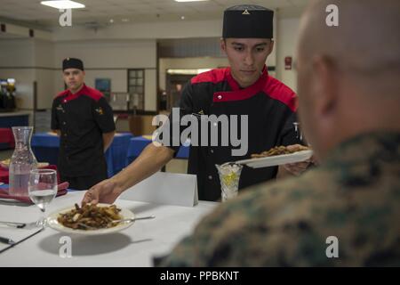 Lance Cpl. Zachery Lacroix, Links, beschreibt die Mahlzeit auf die Richter während Lance Cpl. Jairo Salgado, Center, serviert die Speisen auf die Richter während des Essen Spezialist für das Quartal Wettbewerb im Camp Kinser, Okinawa, Japan, August 30, 2018. Lacroix und Salgado sind beide Food Service Spezialisten mit Sitz Bataillon, 3rd Marine Division. Lacroix ist ein Eingeborener von Lakewood, New York, und Salgado ist ein Eingeborener von San Francisco. Stockfoto