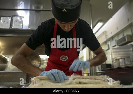 Lance Cpl. Jairo Salgado bereitet ein Dessert für Food Service Spezialist für das Quartal im Camp Kinser, Okinawa, Japan, August 30, 2018. Salgado ist ein Lebensmittel Service Specialist mit Sitz Bataillon, 3rd Marine Division und ist ein Eingeborener von San Francisco. Das Dessert war eine Banane in klebrigen Reis gewickelt und mit Mango Sirup beträufelt. Stockfoto