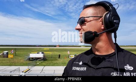 Us Air Force Master. Sgt. Chris Schneider, F-16 Viper Demonstration Team (VDT) Betriebsleiter, steht an Zeigen Sie auf die Mitte der Burke Lakefront Airport Flug online während der Cleveland National Air Show in Cleveland, Ohio, Sept. 1, 2018. Schneider kommentierte Demonstration seines Teams als Maj. John Waters, F-16 VDT Pilot, Precision aerial Manöver in einem F-16 Fighting Falcon durchgeführt. Stockfoto