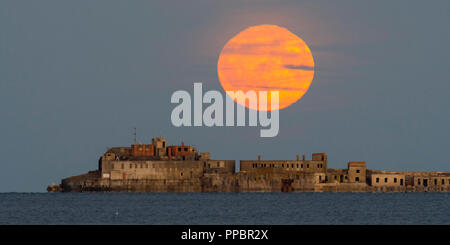 Dorchester, Dorset, Großbritannien. 24. September 2018. UK Wetter. Die Harvest Moon erhebt sich hinter dem historischen des 19. Jahrhunderts Portland Wellenbrecher Fort auf der äußeren Mole Portland Harbour in Dorset. Der jetzt aufgegebenen fort Auch bekannt als Karierten Fort wurde zwischen 1868 und 1878 erbaut und steht unter Denkmalschutz. Foto: Graham Jagd-/Alamy leben Nachrichten Stockfoto