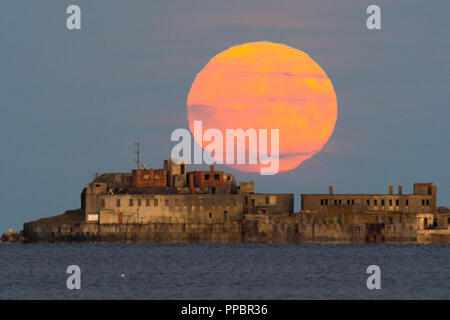 Dorchester, Dorset, Großbritannien. 24. September 2018. UK Wetter. Die Harvest Moon erhebt sich hinter dem historischen des 19. Jahrhunderts Portland Wellenbrecher Fort auf der äußeren Mole Portland Harbour in Dorset. Der jetzt aufgegebenen fort Auch bekannt als Karierten Fort wurde zwischen 1868 und 1878 erbaut und steht unter Denkmalschutz. Foto: Graham Jagd-/Alamy leben Nachrichten Stockfoto