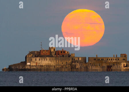 Dorchester, Dorset, Großbritannien. 24. September 2018. UK Wetter. Die Harvest Moon erhebt sich hinter dem historischen des 19. Jahrhunderts Portland Wellenbrecher Fort auf der äußeren Mole Portland Harbour in Dorset. Der jetzt aufgegebenen fort Auch bekannt als Karierten Fort wurde zwischen 1868 und 1878 erbaut und steht unter Denkmalschutz. Foto: Graham Jagd-/Alamy leben Nachrichten Stockfoto