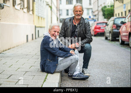 München, Bayern. 04 Sep, 2018. Klaus Eberhartinger (L-R), Sänger der Ersten Allgemeinen Verunsicherung (SAV) und Thomas Spitzer, Gitarrist und Texter der SAV, sitzen auf einem Bürgersteig in einem Interview mit dpa. Die SAB endet nach mehr als 40 Jahren und im Gegensatz zu seiner humorvollen Ruf, Blätter mit ein sehr politisches Album. Credit: Lino Mirgeler/dpa/Alamy leben Nachrichten Stockfoto