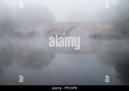 Sonnig-on-Thames, Berkshire. 25. Sep 2018. UK Wetter: einer kalten herbstlichen Nacht schnell Erwärmung in der Morgendämmerung führte zu schweren Dunst und Nebel bei Sonning Brücke auf der Themse heute Morgen. © Danny Callcut/Alamy leben Nachrichten Stockfoto