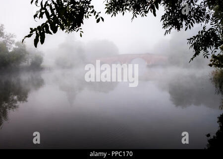 Sonnig-on-Thames, Berkshire. 25. Sep 2018. UK Wetter: einer kalten herbstlichen Nacht schnell Erwärmung in der Morgendämmerung führte zu schweren Dunst und Nebel bei Sonning Brücke an diesem Morgen. © Danny Callcut/Alamy leben Nachrichten Stockfoto