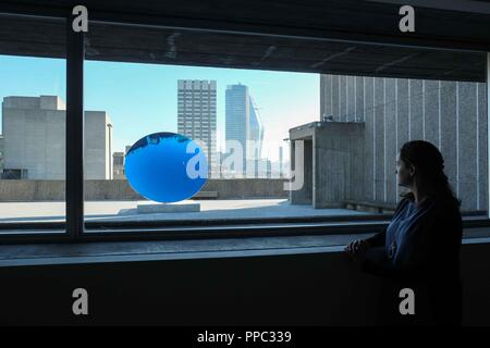 London, den 25. September 2018: eine Gallery Assistant wirft mit Anish Kapoors Arbeit Himmel Spiegel, Blau, 2016. Platz Laufräder in Hayward Gallery verfügt über Kunstwerke über einen Zeitraum von ca. 50 Jahren von den 20 führenden internationalen Künstlern. Platz Laufräder in Hayward Gallery läuft vom 26. September 2018 bis zum 6. Januar 2019. Credit: Claire Doherty/Alamy leben Nachrichten Stockfoto