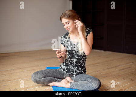 Junge Frau glücklich Ihr Lieblingslied zu singen, während der Wiedergabe von Musik auf dem Boden sitzend mit Kopfhörern. Stockfoto