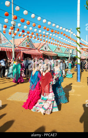 Spanische Frauen tragen flamenco Kleider, bunte Markisen, Portonovo, Feria de Abril in Sevilla, Andalusien, Spanien Stockfoto