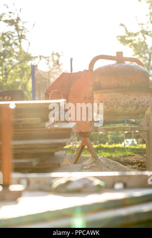 Baustelle Hintergrundbeleuchtung durch helles Sonnenlicht - Bretter, und Cement Mixer an sonnigen Baustelle. Stockfoto