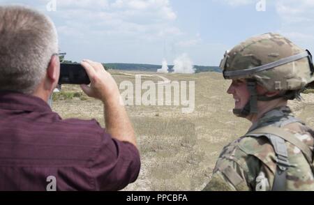 Spc. Heather M. Cote, ein Spezialist der 197th Field Artillery Brigade, N.H. Army National Guard, lächelt, als ihre zivilen Arbeitgeber, John Mercier zeichnet eine HIMARS Rocket Launch Demonstration am 12.08.14, 2018 in Camp Äsche, mich Mercier, und Othe Arbeitgeber, besuchten ihre Bürger - Soldat Mitarbeiter während ihrer jährlichen Schulung als Teil einer Tour mit der N.H. Arbeitgeber Unterstützung des Schutzes und der Reserve. ( Stockfoto