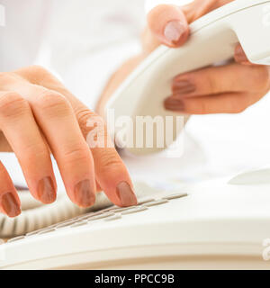 Nahaufnahme der weiblichen Telefon operator Wählen einer Telefonnummer einen wichtigen geschäftlichen Anruf auf weißem Telefon. Stockfoto