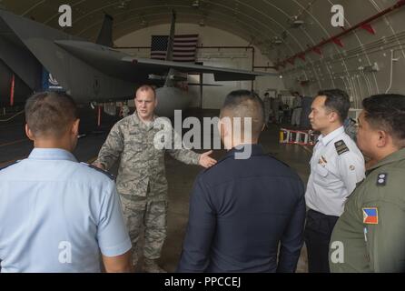 Us Air Force Master Sgt. Benjamin Bouvy, 18 Wartung Gruppe laden Standardisierung Crew Chief, Slips Offiziere der Alliierten und Partner Nationen über die Logistik der Laden von Munition zu einer F-15 Eagle während der 2018 Fighter Logistik und Sicherheit Symposium 12.08.21, 2018, bei Kadena Air Base, Japan. Das Symposium ermöglichte Air Force Offiziere aus Australien, Indonesien, Japan, den Philippinen, Singapur und Thailand zu Fighter Support Units zum 18 Flügel zugeordnet und Interagieren mit Flieger, die den Fighter Mission zu unterstützen. Stockfoto