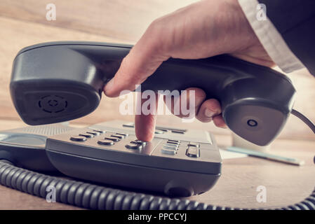 Nahaufnahme der Geschäftsmann ein Telefonat über eine Telefonnummer auf einer klassischen schwarzen Festnetz Gerät mit Retro blass aussehen. Stockfoto