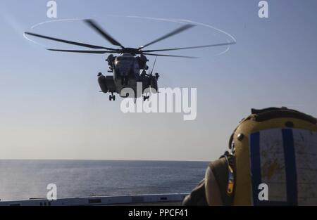 Atlantik (Aug. 26, 2018) der Luftfahrt Bootsmann Mate (Handling) 3. Klasse Devin Lewis Uhren eine CH-53 Super Hengst Hubschrauber zugeordnet zu den "Schwarzen Ritter" der Marine Medium Tiltrotor Squadron (VMM) 264 Abstieg auf dem Flugdeck des amphibious Transport dock Schiff USS Arlington LPD (24) Während der Carrier Strike Group (CSG 4) amphibische bereit, Gruppe, Marine Expeditionary Unit Übung (ARGMEUEX). Kearsarge Amphibious Ready Gruppe und 22 Marine Expeditionary Unit sind die Verbesserung der gemeinsamen Integration, die Letalität und kollektiven Fähigkeiten des Navy-Marine Corps Team durch gemeinsame planni Stockfoto