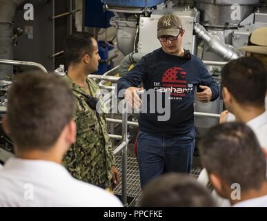 Rumänien (Aug. 27, 2018) Christopher Johnson, einen öffentlichen Dienst marine und Erster Ingenieur an Bord der Speerspitze-Klasse expeditionary schnellen Transport ship USNS Carson City (T-EPF 7), gibt eine Tour des Schiffes Maschinenraum Rumänische militärische Mitglieder in Constanta, Rumänien, Nov. 27, 2018. Carson City ist die siebte von neun Expeditionary schnellen Transport von Schiffen im Bestand Military Sealift Command mit einem primären Mission des Zur schnellen Transport von militärischem Gerät und Personal in Theater über seine 20.000-Quadratfuß-Rekonfigurierbaren Mission Bay Area und Platz für 312 Passagiere. Stockfoto