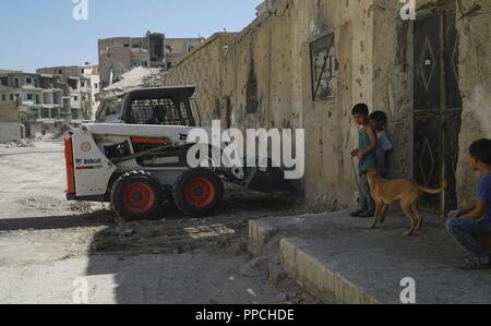 Kinder beobachten Sie, wie die raqqa Unterstützung Platoon klare Schutt von den Straßen von ihrer Nachbarschaft in Raqqa, Syrien, 15. August 2018. Die raqqa Zivilen Rat, mit Unterstützung der Koalition, weiterhin kritisch Dienstleistungen und Infrastrukturen Raqqa zurückzukehren, da die syrischen Demokratischen Kräfte der Stadt von ISIS Kontrolle befreit. Stockfoto