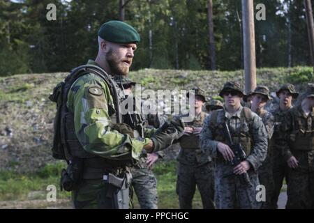 Eine schwedische Küste Ranger mit 1St Marine Regiment gibt eine Reihe Sicherheit kurze während der Übung Archipels Bemühen an Bord Berga Marinestützpunkt, Harsfjarden, Schweden, 22.08.2018. Übung Archipels Bemühen ist ein integrierter Bereich Ausbildung übung, die Einsatzfähigkeit erhöht und verbessert die strategische Zusammenarbeit zwischen der US-Marines und der schwedischen Streitkräfte. Stockfoto