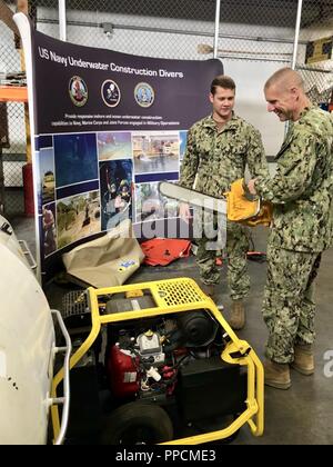 U.S. Navy Konstruktionsmechaniker dritte Klasse Lucas Jackson, zugeordnet zu den UW-Bau Team 2 (UCT 2), erläutert die Möglichkeiten der Unterwasser hydraulische Werkzeuge zum dreißigsten Schiffsbaus Regiment Commodore, Kapitän Steven Stasick, während einer Tour von Uct 2, in Port Hueneme, Kalifornien, am 24. August 2018. Der Schiffbau auf Kraft (NCF) bietet Aufgabe zugeschnittene, anpassungsfähig und Bekämpfung effektive Planung und Bau Kräfte, die Bereitstellung von Naval Ziele weltweit zu unterstützen und die Logistik für verteilte Flotte zu aktivieren. UCT 2 ist eine wichtige Komponente der NCF, Providi Stockfoto