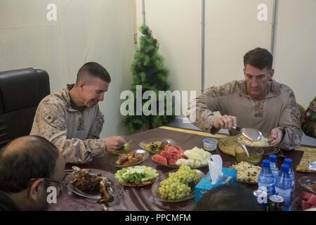 Der Provinz Helmand, in Afghanistan (29 August 2018) - US Marine Corps Brig. Gen. Benjamin T. Watson, Kommandierender General der Aufgabe Force-Southwest und US Marine Corps Oberst Christopher J. Douglas, Senior Berater der 505th Zone der afghanischen nationalen Polizei, teilen sich eine Mahlzeit mit afghanischen Generalmajor Taous, der Helmand nationale Direktion Service Leiter, während ein wichtiger Führer Engagement an der provinziellen Hauptsitz in Lashkargah. Marines reiste in das polizeipräsidium Wahl Sicherheit mit provinziellen Führer zu diskutieren, eine sichere Wahl für die Menschen in der Provinz Helmand zu gewährleisten. Stockfoto