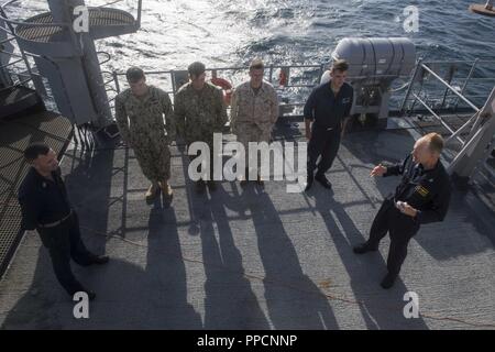 Golf von Aden (Sept. 3, 2018) - Kapitän Gerald Olin, Commander, Amphibischen Squadron 1, spricht mit Matrosen und ein Marine auf der Steuerbordseite der Brücke Flügel Whidbey Island-Klasse dock Landung Schiff USS Rushmore (LSD 47), die während einer planmäßigen Einsatz der Essex Amphibious Ready Group (ARG) und 13th Marine Expeditionary Unit (MEU). Das Essex ARG/13 MEU ist tödlich, flexibel, und anhaltende Navy-Marine Corps Team in die USA 5 Flotte Bereich der Maßnahmen zur Unterstützung der Marine im Einsatz für die Stabilität und Sicherheit in der Region zu gewährleisten, die Verbindung mit dem Mittelmeer und Stockfoto