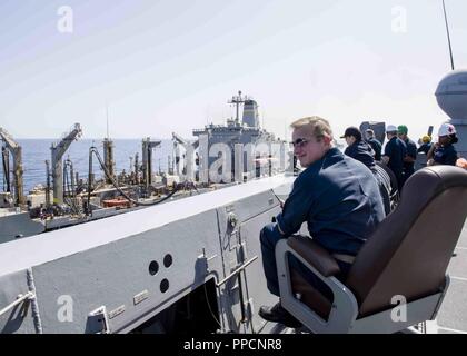 Golf von Aden (Sept. 4, 2018) Kapitän Dennis Jacko, von Sayreville, N.J., kommandierender Offizier der San Antonio-Klasse amphibious Transport dock USS Anchorage LPD (23), über sieht eine Auffüll-anforderung-auf-See mit Fleet Auffüllung öler USNS Laramie (T-AO 203), während auf einer planmäßigen Einsatz von Essex Amphibious Ready Group (ARG) und dem 13 Marine Expeditionary Unit (MEU). Das Essex ARG/13 MEU ist eine tödliche, flexibel, und anhaltende Navy-Marine Corps Team in die USA 5 Flotte Bereich der Maßnahmen zur Unterstützung der Marine im Einsatz für die Stabilität und Sicherheit in der zentralen R zu gewährleisten Stockfoto