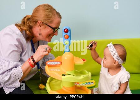 KUWAIT CITY, Kuwait - Maj. Amanda Harrah, 28 Infanterie Division/Task Force Spartan stellvertretender Civil Affairs Officer, verbindet Lächeln mit einem jungen Mädchen im Krankenhaus. Für die letzten zwei Monate, TFS haben Soldaten der Freiwilligenarbeit mit den Kuwait Verband für die Betreuung von Kindern in Krankenhäusern. Stockfoto