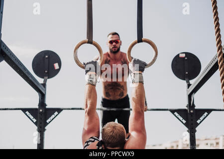 Mann Ausübung hängend auf Gymnastik Ringe und anderen beobachten Stockfoto