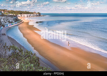 Ebbe in Stein Bay, Broadstairs, Kent, wie Sommer dreht sich bis Herbst, ein einsamer Surfer am Strand spazieren und eine Familie, die auf der Promenade entlang der Seite der Beac Stockfoto