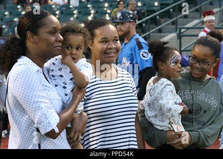 Shani Glas (ganz links), Ehefrau von Sgt. Dennis Glas, Uhren eine Überraschung Video zusammen mit ihrer Familie durch Glas von seinem Einsatz an der Brooklyn Wirbelstürme militärischen Anerkennung Tag in New York geschickt am 31. August 2018. Glas wird auf der 361 Drücken Sie Camp Headquarters aus Fort Totten, New York zugeordnet und ist derzeit im Irak bereitgestellt. (Armee Stockfoto