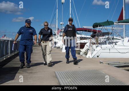 Lt.Cmdr. Kerry Herzog, ein untersuchungsrichter Officer bei Coast Guard Sektor Charleston, Bridget Wyant, der Küstenwache Special Agent, und Petty Officer Third Class Casy Strawn, der bootsmann Mate an der Coast Guard Station Charleston, die Docks des Charleston Harbor Marina August 30, 2018 in Charleston, South Carolina. Herzog, Wyant und Strawn ging die Docks von verschiedenen Marinas in Charleston die Öffentlichkeit über illegale Chartas und Bootfahrtsicherheit zu erziehen. Stockfoto