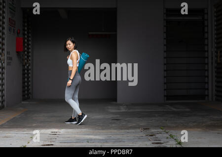 Junge Frau zu Fuß zum Fitnessraum, Yoga, Yoga Matte Stockfoto