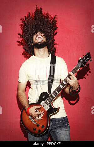 Nahaufnahme von einem stattlichen leidenschaftlich expressive cool Junge brunette Rock Musiker Männer schreien und headbang mit langen Locken in der Luft spielen ele Stockfoto