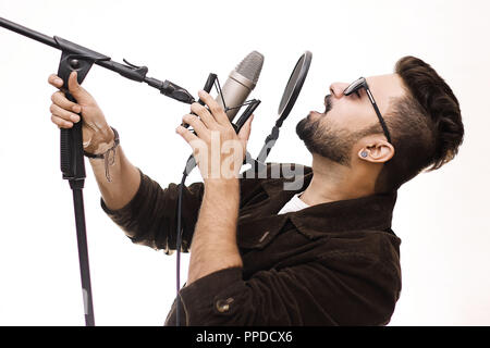 Begabte junge Mann mit dem braunen Fell und Gläser ein Lied singen im Studio Aufnahme Stockfoto