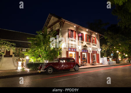 Alte Citroen Traction Avant Auto geparkt vor einem beleuchteten französische Kolonialzeit Gebäude auf einer idyllischen Sakkaline Straße in Luang Prabang, Laos, in der Dämmerung. Stockfoto