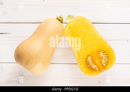 Eine ganze Hälfte von glatten Birnenförmig orange Kürbis waltham Vielzahl flatlay auf weißem Holz Stockfoto