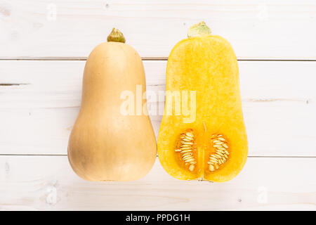 Eine ganze Hälfte von glatten Birnenförmig orange Kürbis waltham Vielzahl flatlay auf weißem Holz Stockfoto