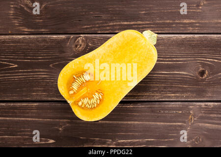 Die eine Hälfte der glatten Birnenförmig orange Kürbis waltham Vielzahl flatlay auf braunem Holz Stockfoto
