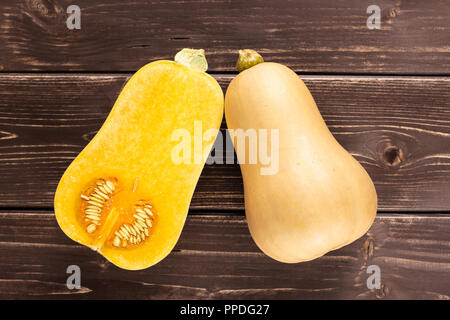 Eine ganze Hälfte von glatten Birnenförmig orange Kürbis waltham Vielzahl flatlay auf braunem Holz Stockfoto