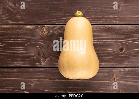 Eine ganze glatte Birnenförmig orange Kürbis waltham Vielzahl flatlay auf braunem Holz Stockfoto