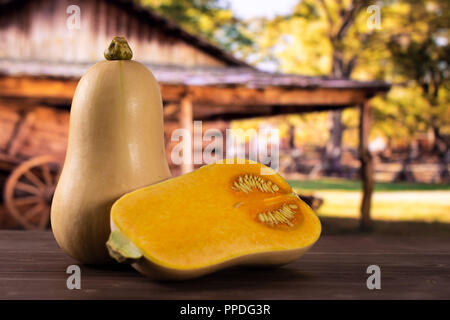 Eine ganze Hälfte von glatten Birnenförmig orange Kürbis waltham Sorte mit Warenkorb im Hintergrund Stockfoto