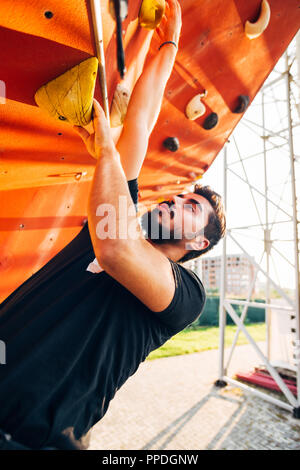 Junger Mann steigt ein im Freien Wand Stockfoto