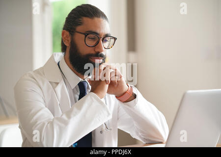 Portrait von männlicher Arzt sitzen vor dem Laptop. Stockfoto
